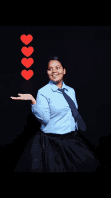 a woman wearing a blue shirt and tie is holding a heart in her hand