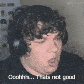a man with curly hair wearing headphones says ooohh thats not good
