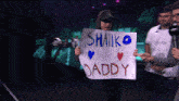a man holding a sign that says " shaik is daddy "