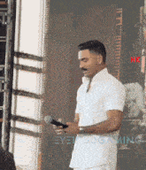 a man in a white shirt is holding a microphone in front of a sign that says hk