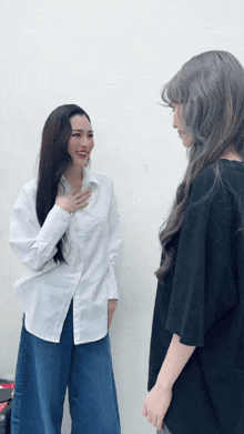 two women standing next to each other one wearing a white shirt
