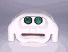 a white object with two green eyes and a smiley face