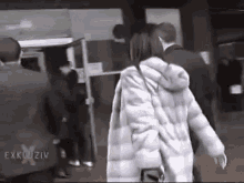 a woman in a fur coat is walking down a street with a man in a suit .
