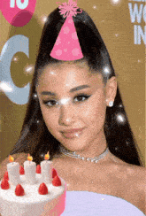 a woman wearing a pink party hat holds a cake
