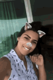 a woman wearing cat ears on her nose smiles at the camera