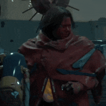 a man in a red cape is standing next to a robot in a dark room
