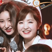 a woman holding a microphone next to another woman with a sign that says izone