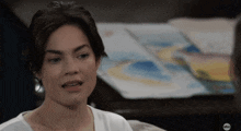 a woman sitting on a couch with a painting in the background and the abc logo on the bottom