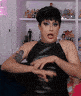 a woman with a tattoo on her arm is wearing a black dress and hat