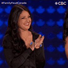 a woman applauds in front of a microphone while wearing a name tag that says q