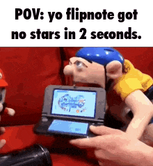 a person is playing a video game on a nintendo 3ds while a puppet looks on .