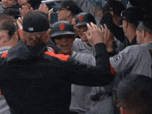 a group of giants baseball players high five each other in the dugout