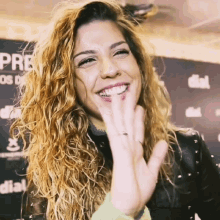 a woman with curly hair is smiling and giving a high five in front of a sign that says dial