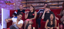 a group of people sitting on a red couch with a sign that says en vivo on it