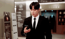 a man in a suit and tie looking at his phone