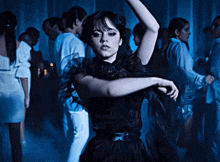 a woman in a black dress is dancing in a crowded room
