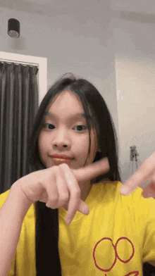 a young girl wearing a yellow shirt with a red circle on it