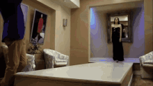 a woman in a black dress is walking down a white runway
