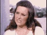 a woman with long hair is making a funny face while standing next to a pole .