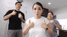 a woman wearing a smart watch gives a thumbs up while a man holds a lemon
