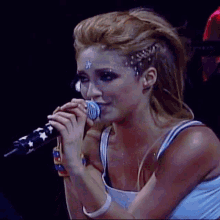 a woman is singing into a microphone with a star on her forehead