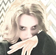 a woman covering her mouth with her hands in front of a chevron pattern