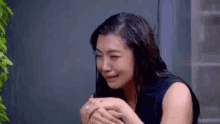 a woman is crying with her eyes closed while holding her hands to her face .