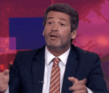 a man in a suit and tie is making a gesture with his hand