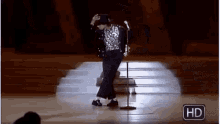 a man is dancing on a stage with a microphone in front of him .