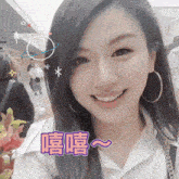 a woman wearing hoop earrings and a white shirt smiles