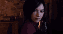 a woman is holding a gun and looking at the camera in a dark room .