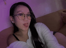 a woman wearing glasses is sticking her tongue out while sitting on a couch