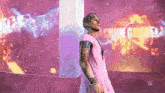 a man in a pink shirt is standing in front of a screen that says live on it