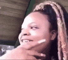 a close up of a woman with dreadlocks making a funny face with her hand on her chin .