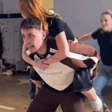 a man is carrying a woman on his back in a room .