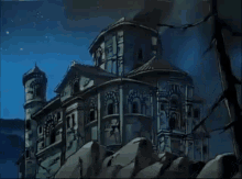 a castle is sitting on top of a rocky hill at night with a tree in the foreground .