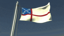 a white flag with a red cross on it is flying in the wind