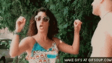 a woman wearing sunglasses is dancing in front of a tree .