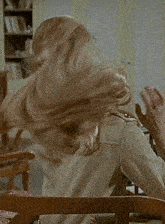 a woman with long blonde hair is sitting in a chair with her hair blowing in the wind .