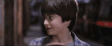 a young boy wearing glasses and a plaid shirt looks to the side