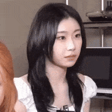 a young woman with long black hair is sitting in a living room .