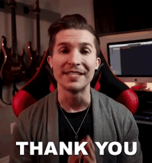 a man is sitting in a red and black chair and saying thank you