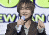 a man in a suit holds a microphone in front of a screen that says new nc