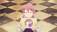 a girl with pink hair is holding a piece of paper with a picture of a man and woman on it