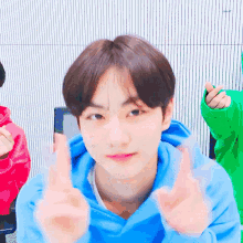 a young boy in a blue hoodie is making a heart shape with his hands .