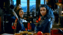 a woman in a costume is sitting at a table with a glass of wine and an apple .