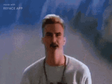 a man with a mustache is standing in front of a colorful wall