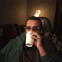 a man wearing sunglasses is holding a cup in his hand