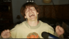 a man wearing headphones is singing into a microphone while wearing a yellow shirt