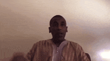 a man in a tan and white striped shirt is speaking into a microphone